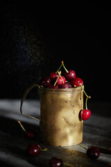 Cherry berries in a copper mug, spray on the background.