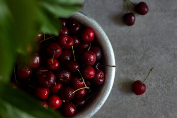 Cherry fruits in an aluminum bowl, spray on the background.