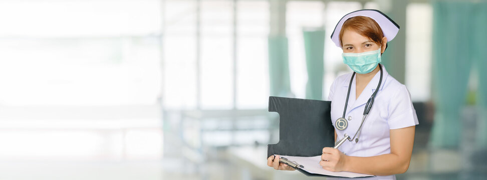 Asian female nurse writing medical report on Ward bed Hospital Blurred background for wide banner background design
