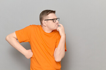 Portrait of funny man touching lips with finger and thinking hard