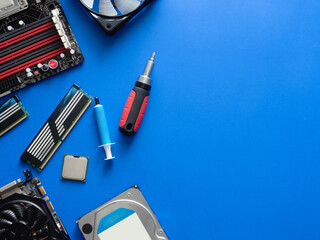 top view of computer parts with harddisk, ram, CPU, graphics card, and motherboard on blue table background.