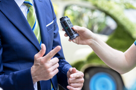 Reporter holding voice recorder making media interview with politician or business person