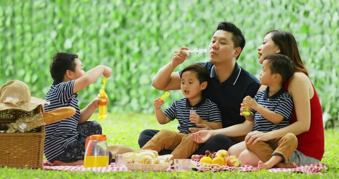 Parents and their twin sons blowing soap bubbles