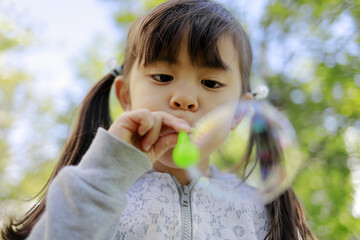 緑の中でシャボン玉で遊ぶ幼児(5歳児)