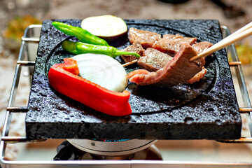 Japanese barbecue, grilled meat and vegetables on a lava stone plate