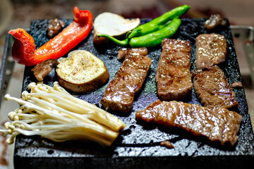 Japanese barbecue, grilled meat and vegetables on a lava stone plate