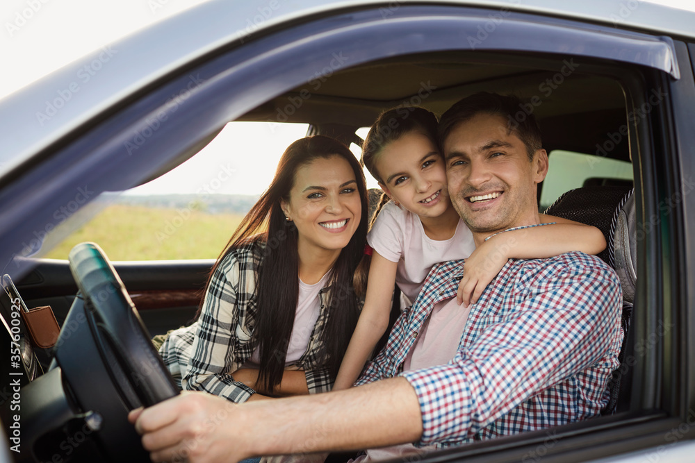 Wall mural Happy family on the road in a car on an adventure vacation trip.