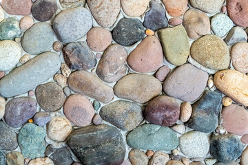 Stone wall as a background. Masonry made of natural, polished by the sea, cobblestones. Multi-colored, natural stones in the interior.