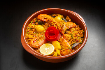 Seafood paella in ceramic bowl on dark wooden background. Rice with seafood.