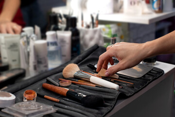 Makeup cosmetics. Work set for a beautician. Brushes, palettes, blush, pigments, eye shadow, mascara. Beauty, fashion and style industry. Sparkles and vibrant colors. Hand takes sponge