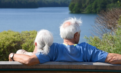 Verliebtes Rentner-Paar Arm in Arm den Ausblick an einem See genießend