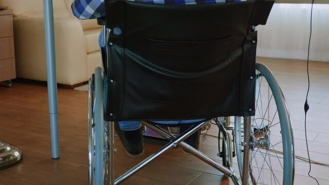 Doctor instructions during video call for disabled man in wheelchair. Handicapped invalid paralysed freelancer, immobilized entrepreneur working from home, ilness and disability