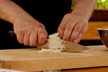the chef cuts the onion to fry on the Board. hands with a knife in the frame.