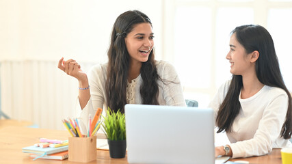 University students are sitting together in front of a computer laptop at the working desk.