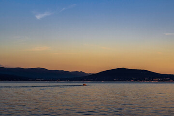 Pleasure boat floating in the bay during a summer sunset.