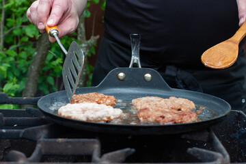 the cook roasts the cutlets in a pan over the fire. food on the grill in nature. picnic.