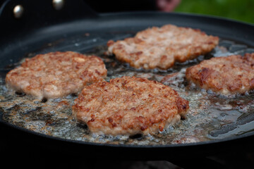 the cook roasts the cutlets in a pan over the fire. food on the grill in nature. picnic.