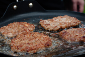 the cook roasts the cutlets in a pan over the fire. food on the grill in nature. picnic.