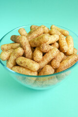 glass bowl with gluten-free corn sticks with cocoa on a blue background side view . sweet Breakfast snacks for children