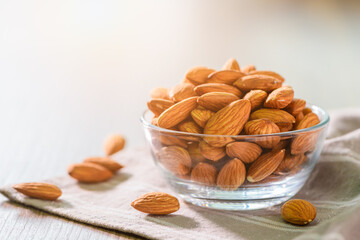 Almonds nuts   peeled in glass bowl on wood table with sun light on morning.