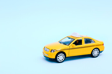 Urban taxi and delivery service concept. Toy yellow taxi car model on blue background. Copy space for text, banner. Online mobile application order taxi service.