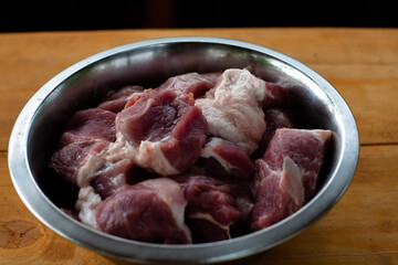 pork shoulder cut into pieces. raw meat in a bowl. for pickling.