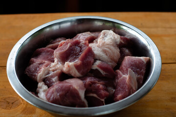pork shoulder cut into pieces. raw meat in a bowl. for pickling.