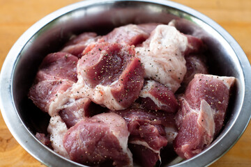 pork shoulder cut into pieces. raw meat in a bowl. for pickling.