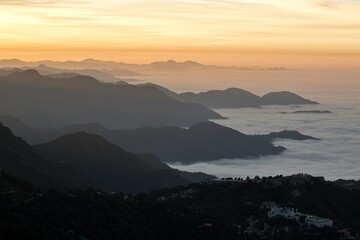 landscape view of sunrise over the mountains with fog & clouds