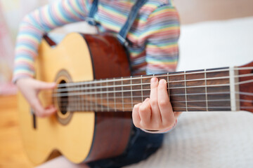 Little girl plays the guitar at home.