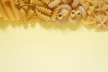 Italian pasta of several types on a yellow background, close-up