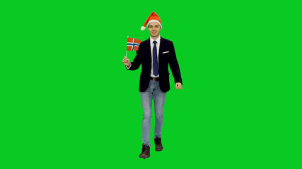 Young stylish man in santa hat walking with waving flag of Norway on green screen background, Full body, Chroma key