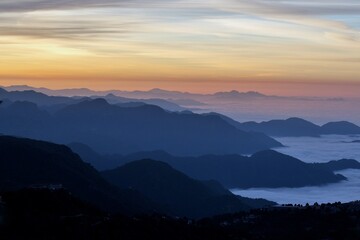 landscape view of sunrise over the mountains with fog & clouds
