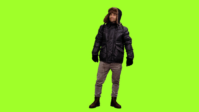 Casual man in winter clothes and gloves standing on green background, Chroma key