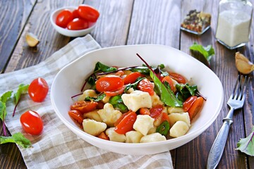 Lazy dumplings or gnocchi from cottage cheese with toppings of stewed tomatoes and young beet tops