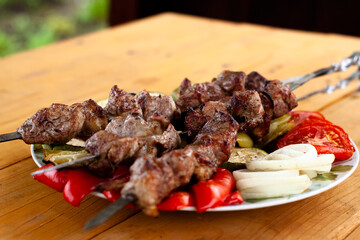 a tray with meat on skewers sprinkled with herbs on grilled vegetables