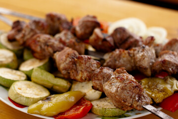 a tray with meat on skewers sprinkled with herbs on grilled vegetables