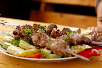 a tray with meat on skewers sprinkled with herbs on grilled vegetables