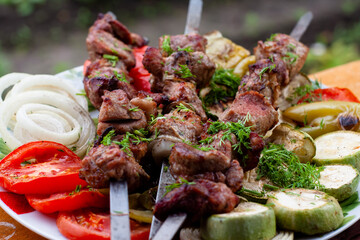 a tray with meat on skewers sprinkled with herbs on grilled vegetables