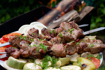 a tray with meat on skewers sprinkled with herbs on grilled vegetables