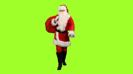 Front view of Santa Claus carrying gifts in sack on green background