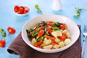 Lazy dumplings or gnocchi from cottage cheese with toppings of stewed tomatoes and young beet tops