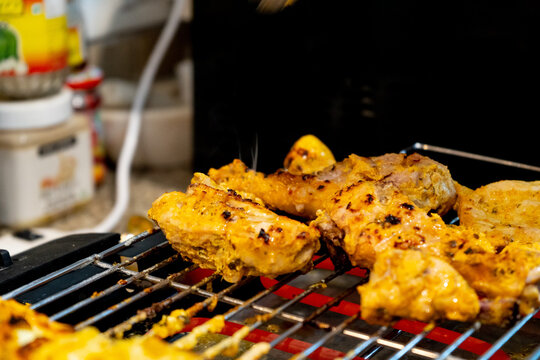 chicken grilling over a hot electric grill with hot rods at home barbeque