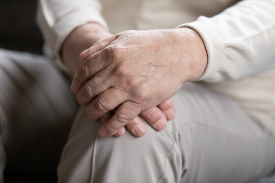 Close Up Elderly Lonely Man Folded Wrinkled Hands On Lap, Mature Old Grandfather Sitting Alone, Thinking About Past, Lost In Thoughts, Aging Process Concept, Loneliness And Solitude