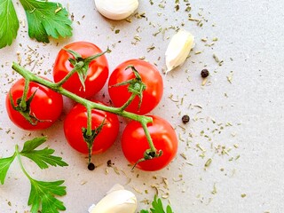 Tomato, spices, pepper, garlic, parsley, herb. Vegan diet food, creative cherry tomato composition isolated on gray background. Organic fresh vegetables. Copy space for text, top view.