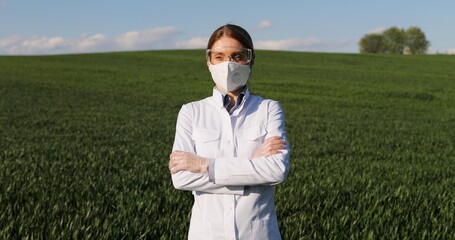 Portrait of Caucasian beautiful female ecologist scientist in white gown, mask and googles standing...