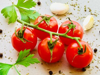 Fresh red cherry tomatos, spices, pepper, garlic, parsley, herb on gray background