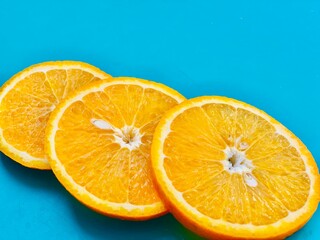 Fresh orange slice on blue background closeup. Flat lay, copyspace, top view.