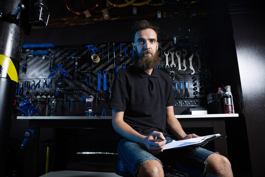 Bicycle Workshop Technician Doing Administrative Work. Bicycle mechanic writing in his checklist notebook. Bicycle mechanic at work. Caucasian worker writing on clipboard in bicycle shop