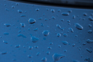 Raindrops on a blue car close-up.